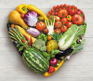 Essential fruits and vegetables placed in a beautiful heart shape on a wooden surface, teaching you to eat healthy is the nutrition group on Hala Yalla